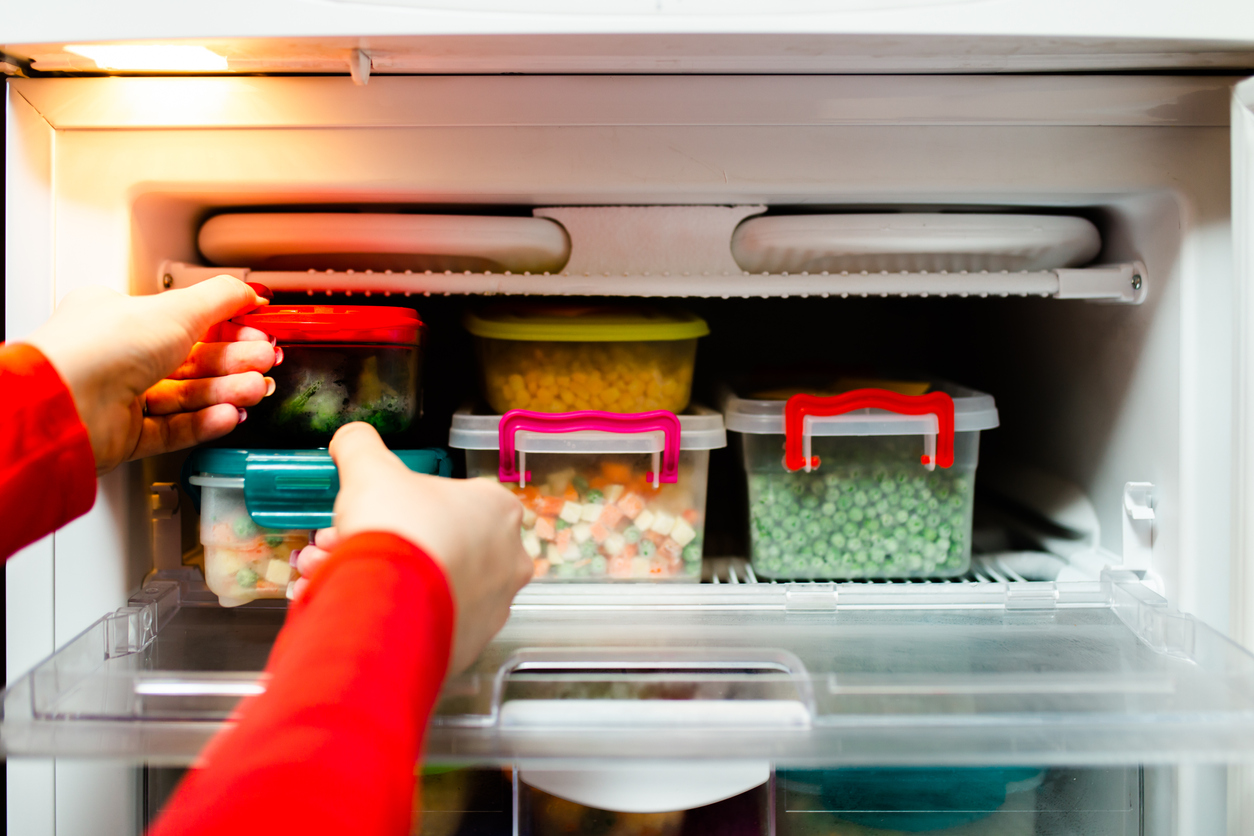 person stocking an upright freezer