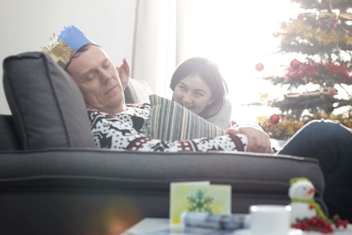 Dad asleep in a chair about to be poked by young child