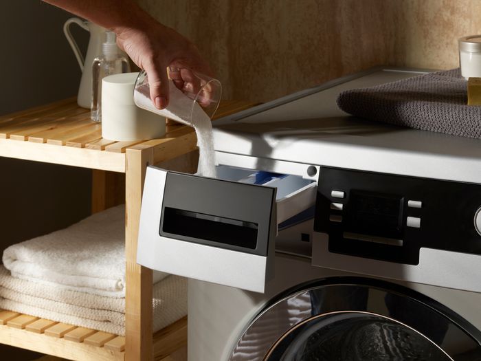 closeup of hand pouring powder detergent in dispenser