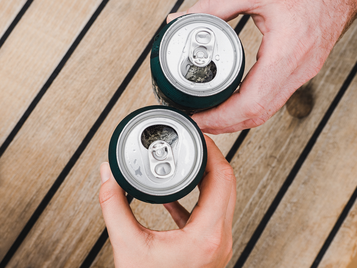 Two open soda cans clinking in a cheers