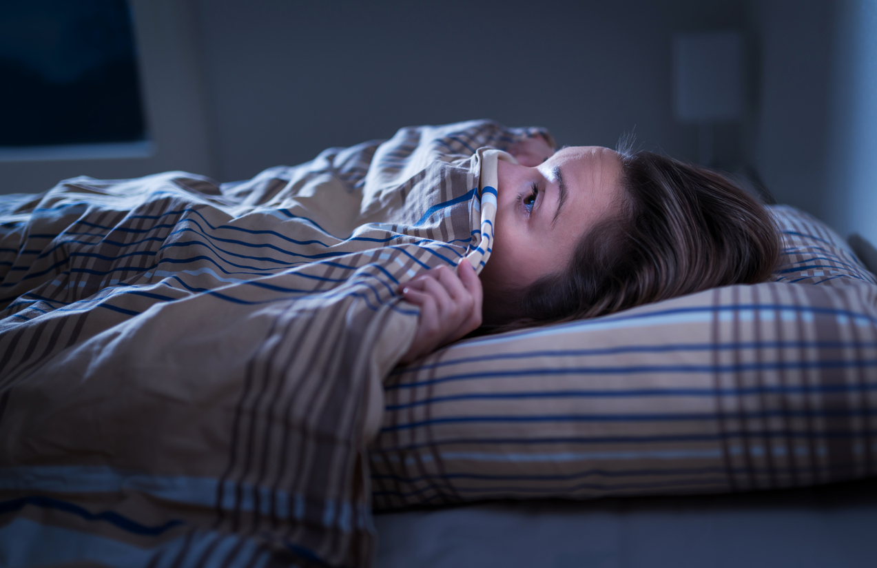woman scared and peeking out from under covers