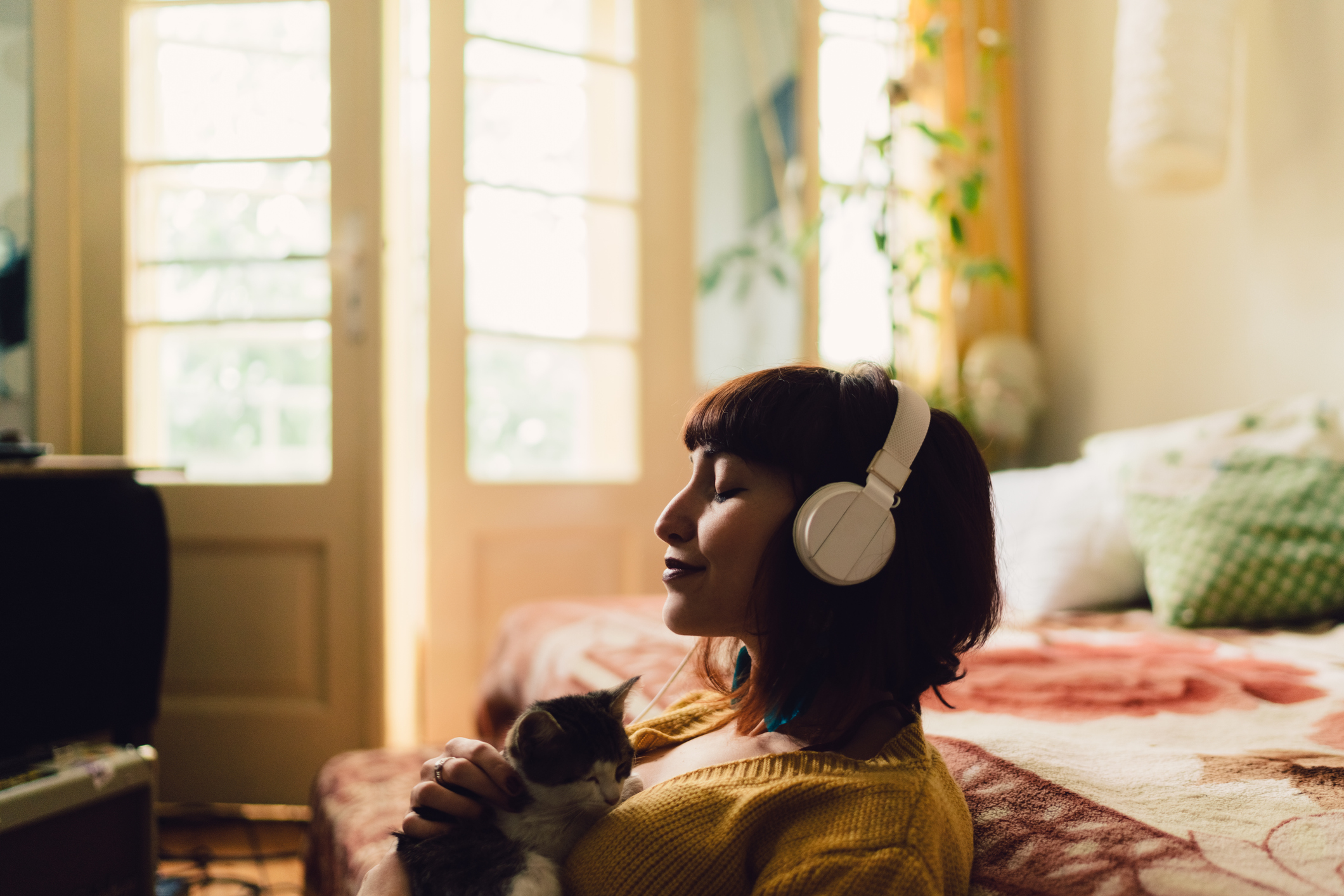 woman with headphones on holding a cat