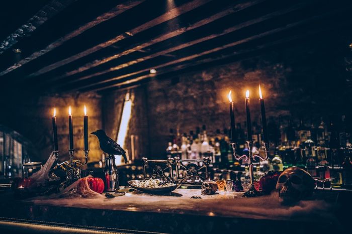 Spooky dining room with dim candlelight, potion bottles, and fake ravens.