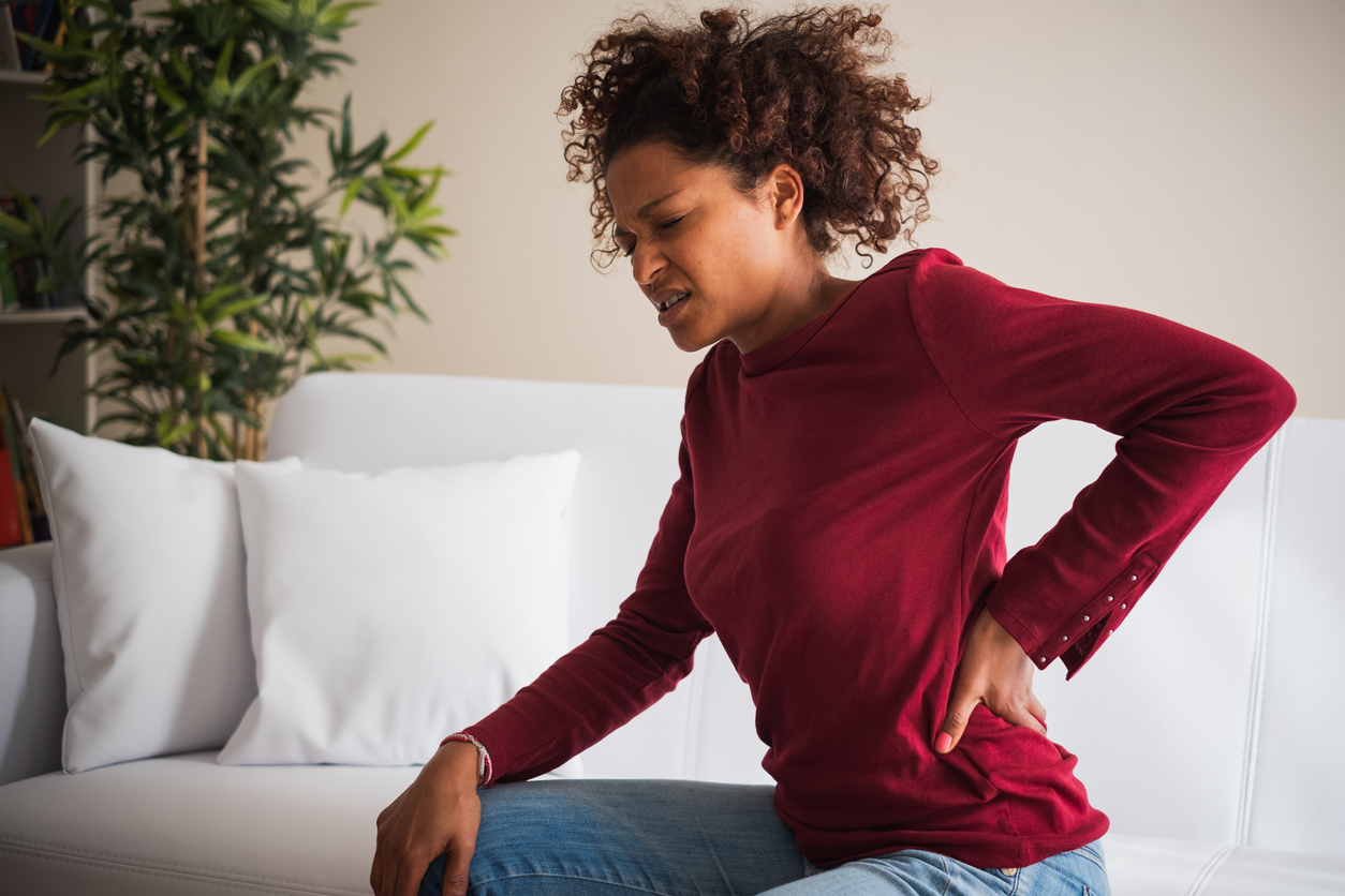 a woman sitting down and looking in pain while holding back