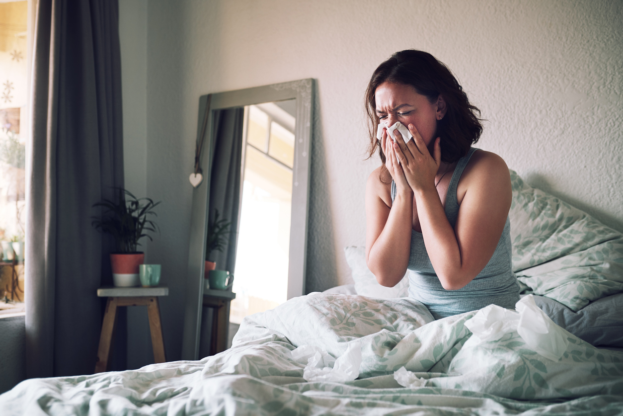 a girl blowing her nose in bed