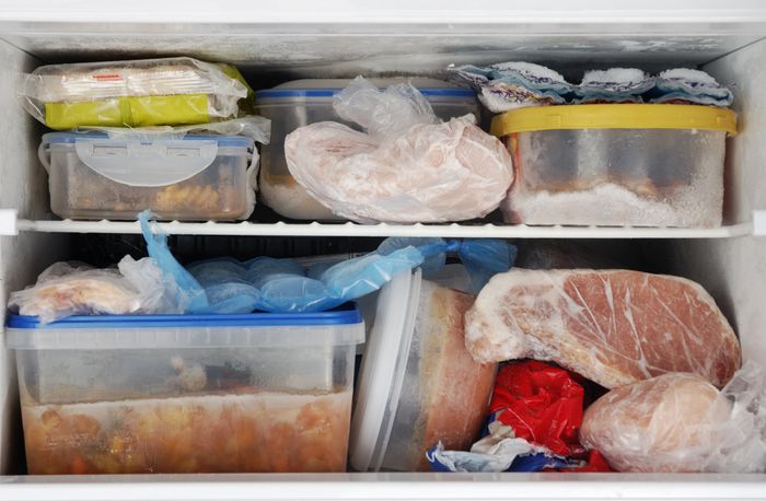 A freezer packed full of food and containers.