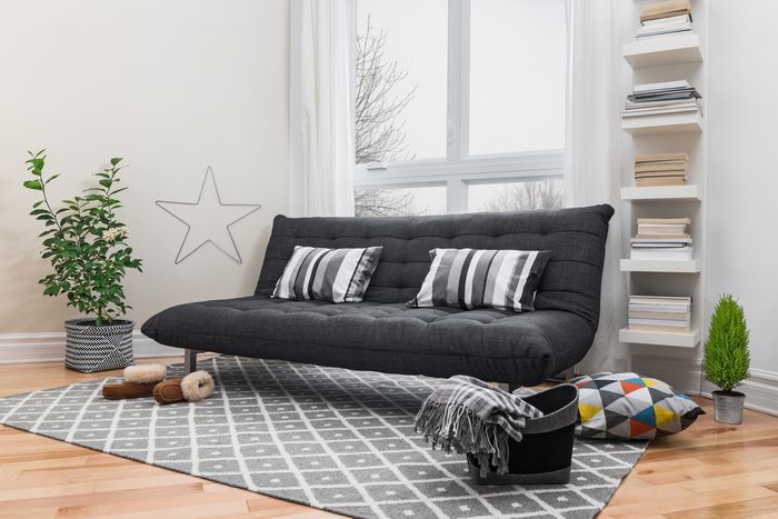 A black futon sofa in a bright, transitional-style loft apartment.