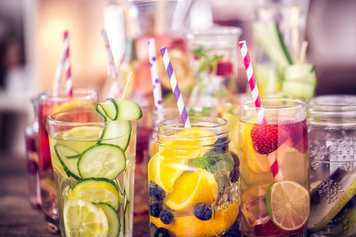 Several mason jars full of water and various fruits.
