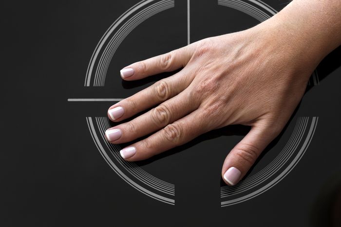 A hand placed on top of the surface of an induction cooktop.