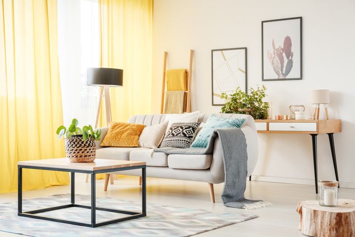 A sunny, Scandinavian-style living room with blankets draped over a couch.