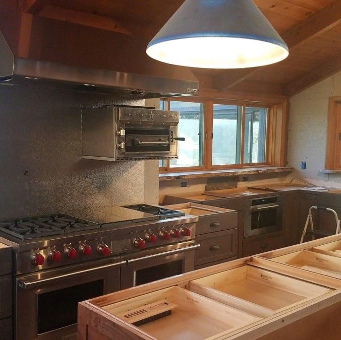 A professional kitchen with a wall-mounted kitchen salamander above the range.