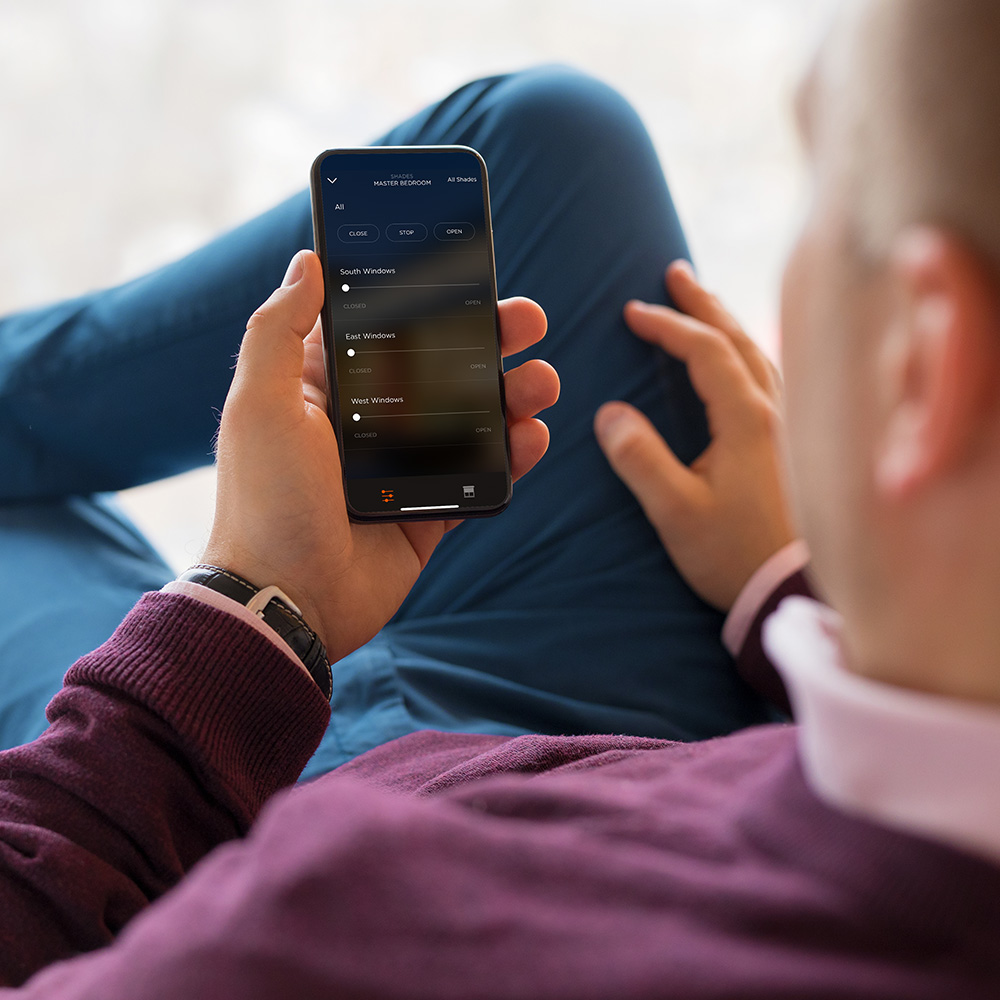 Man holding smart phone controlling level of motorized shades