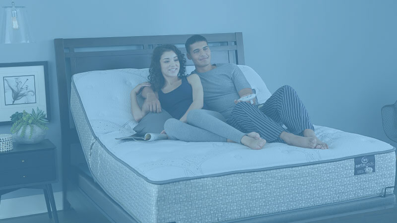 couple watching tv laying on an adjustable bed