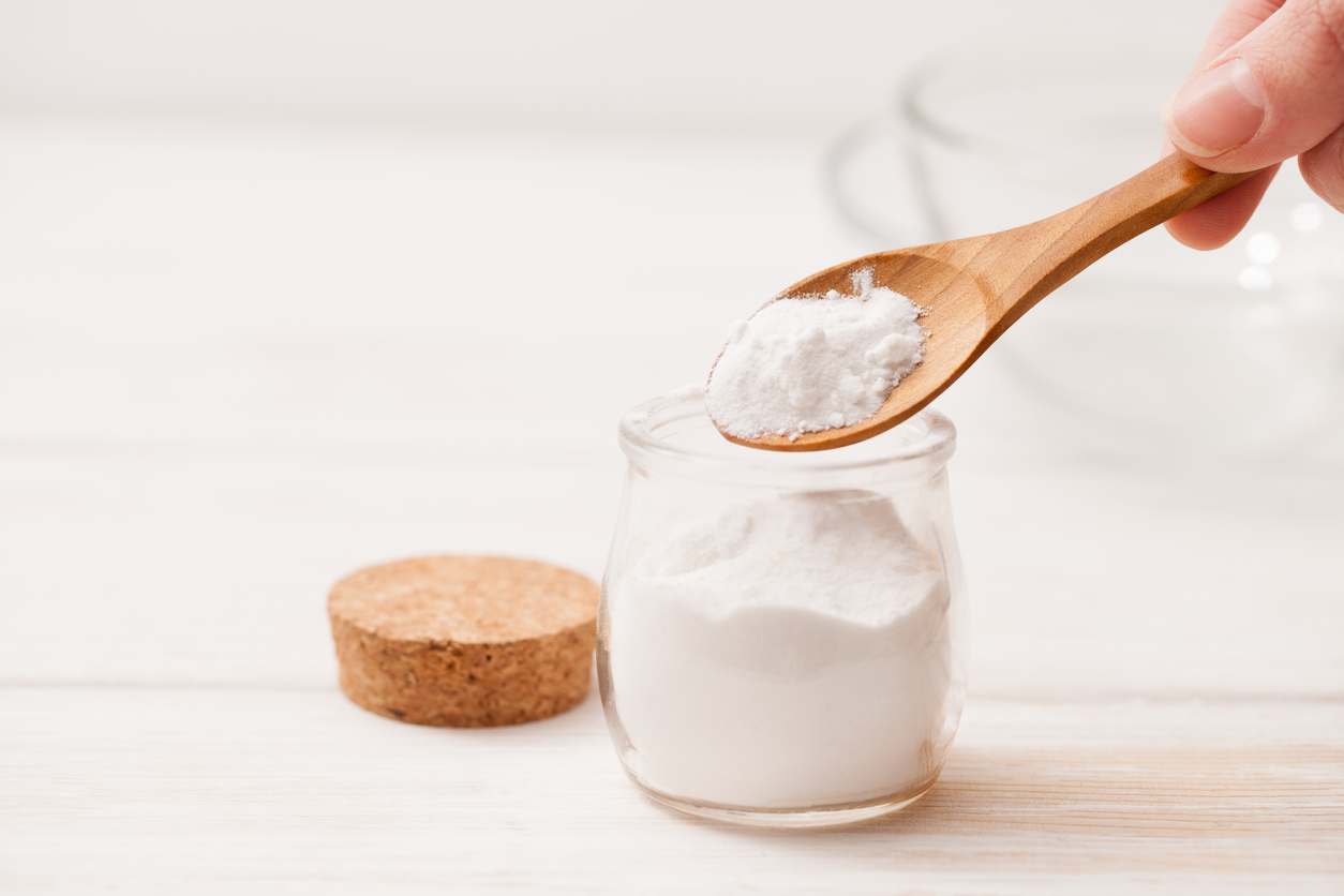 wooden spoon scooping baking soda out of class container