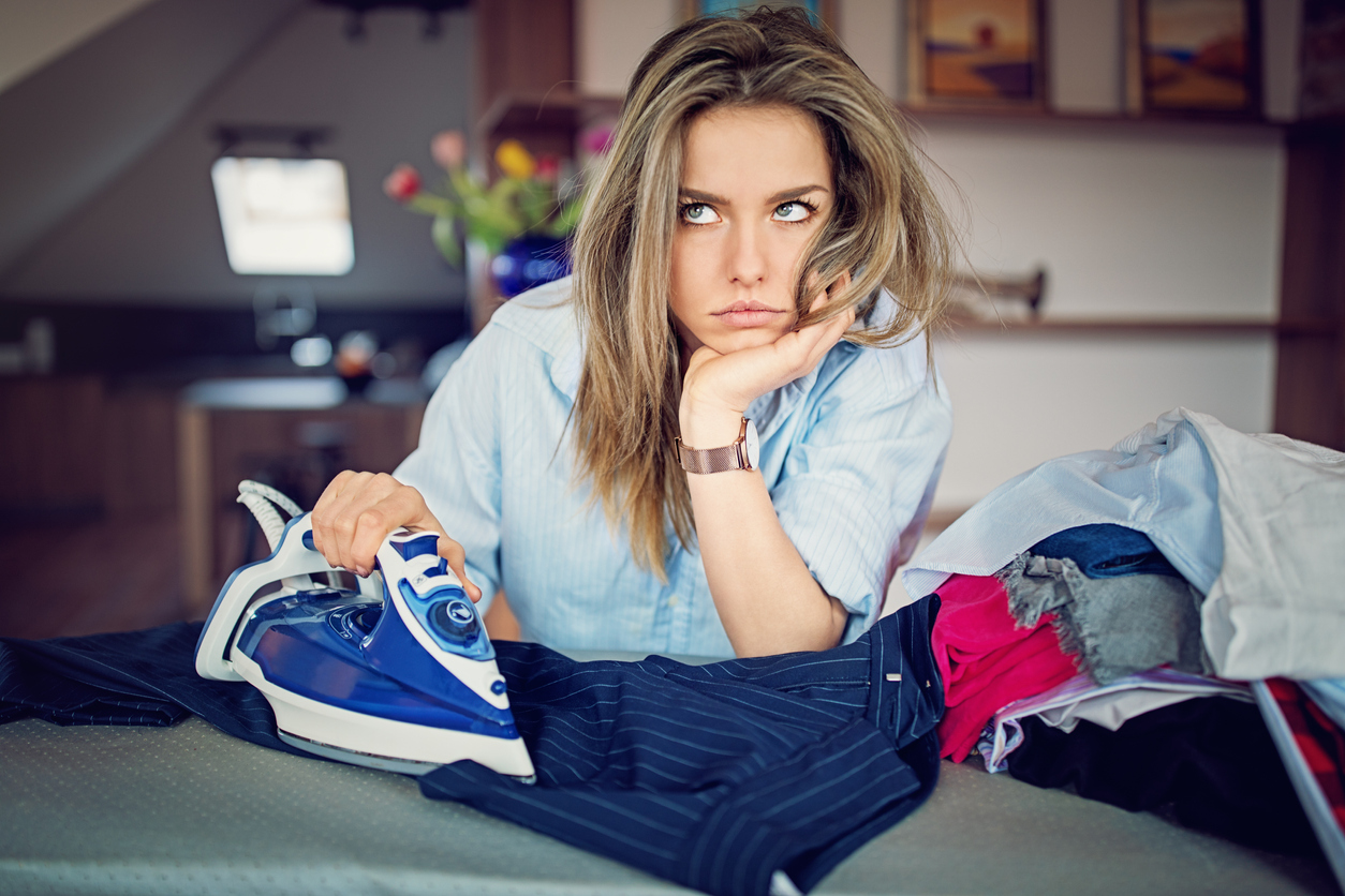 Girl unhappily ironing a shirt