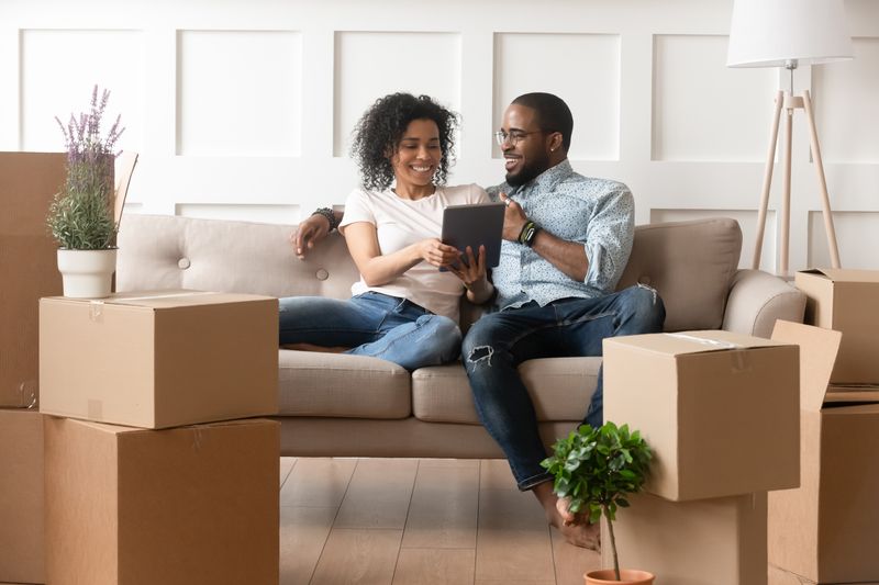 Couple sitting on couch looking at ipad together.