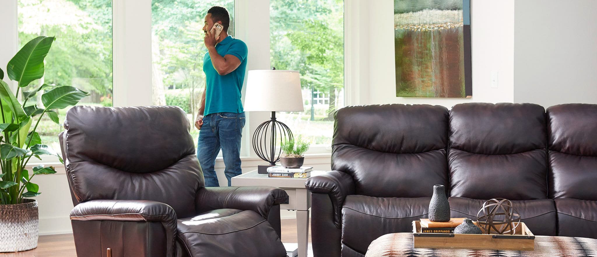 Man talks on the phone behind brown leather La-Z-Boy recliners