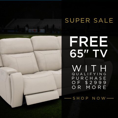 White leather reclining sofa positioned on a football field background, with promotional text reading “Super Sale,” “Free 65” TV with qualifying purchase of $2999 or more,” and “Shop Now.”