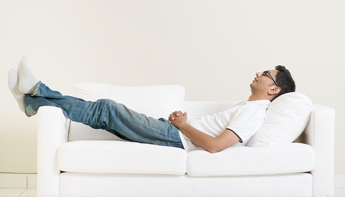 Man laying on a couch that is too short forhim