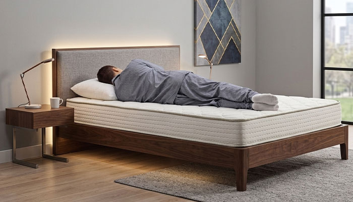 Man lying on his side testing a new mattress at home during a mattress trial