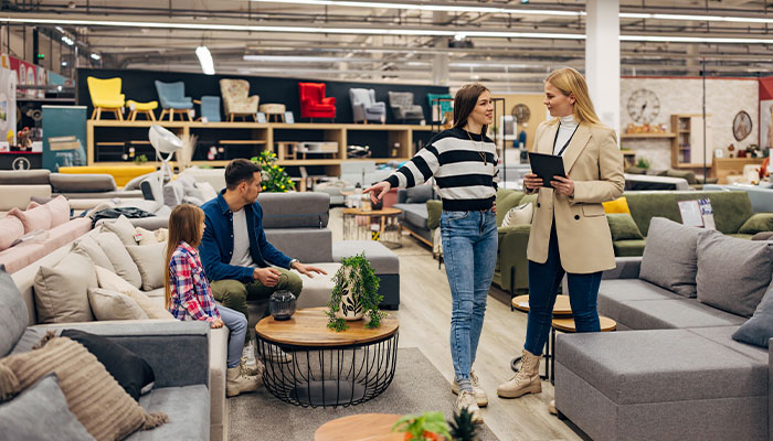 Sales associate helping a family choose living room furniture in a furniture showroom