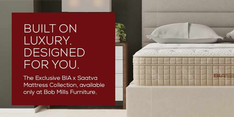 Luxury mattress bedroom scene featuring a BIA x Saatva mattress on a modern upholstered bed. A red promotional panel reads, “Built on luxury. Designed for you. The Exclusive BIA x Saatva Mattress Collection, available only at Bob Mills Furniture.”