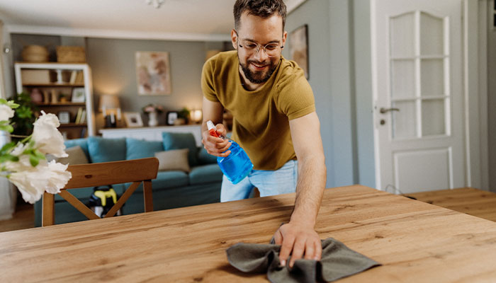 Man cleaning a wooden table with cloth