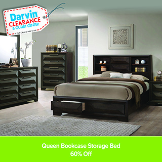 Outdoor patio set with a rectangular dining table and six cushioned wicker chairs arranged on a stone patio beside a house with sliding glass doors and potted plants. Darvin Furniture & Mattress branding appears, with text reading “All Weather Wicker. 5 Year Frame Warranty.”