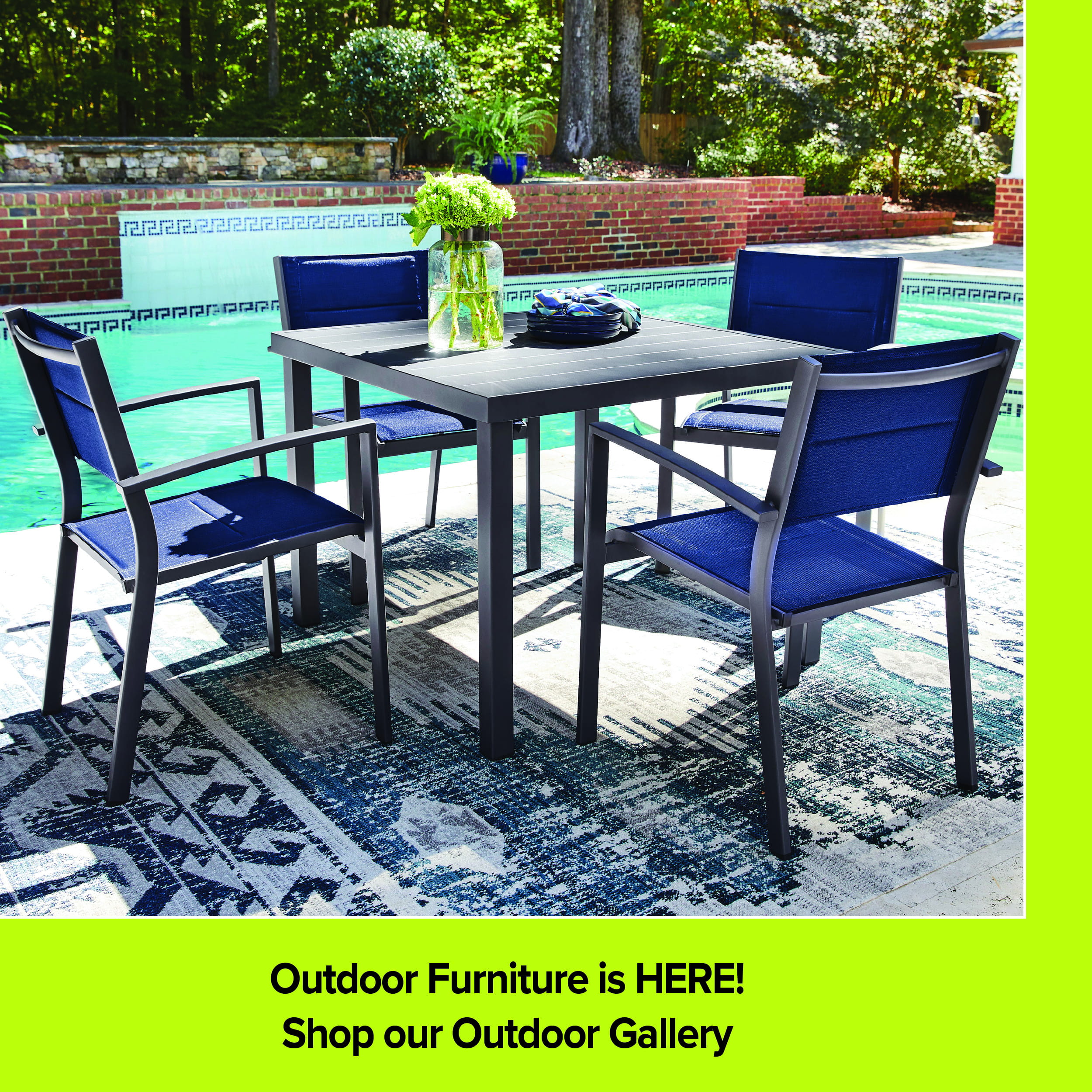 An outdoor dining set from Darvin Furniture & Mattress featuring a square dark metal slatted table and four matching armchairs with blue mesh fabric seats and backs. The set is arranged on a blue and grey patterned rug by a swimming pool. A lime green footer reads 'Outdoor Furniture is HERE!' and 'Shop our Outdoor Gallery'.
