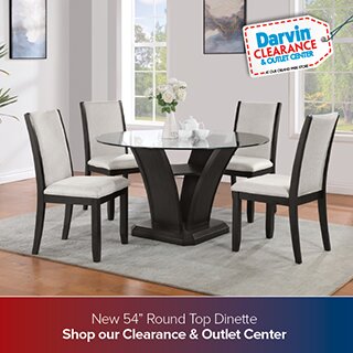 A dining room set from the Darvin Clearance & Outlet Center featuring a 54 inch round glass-top table with a dark pedestal base and four white upholstered chairs with dark wood frames. The bottom banner reads 'New 54 inch Round Top Dinette Shop our Clearance & Outlet Center'.