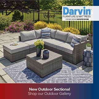 A modern outdoor patio setting featuring a grey wicker sectional sofa with light grey cushions and a matching square coffee table on a blue patterned rug. The bottom banner reads 'New Outdoor Sectional Shop our Outdoor Gallery'.