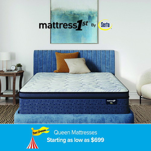 A promotional advertisement for a mattress sale. The image features a mattress with a white and blue quilted top pattern and a textured royal blue side panel. The mattress is displayed on a matching blue upholstered bed frame with a vertical-channeled headboard against a plain white wall. Above the headboard hangs a large abstract painting with shades of teal, blue, and white, overlaid with the text 'mattress1st By Serta'. The bed is styled with one textured orange pillow and one smooth beige pillow. To the left is a small wooden nightstand with a lamp and clock, and part of a white accent chair is visible on the right. A yellow 'Tent Special' flag and a red-and-white striped tent graphic appear in the bottom left corner. A solid blue banner running along the bottom reads 'Queen Mattresses' followed by 'Starting as low as $699' in clean white text.