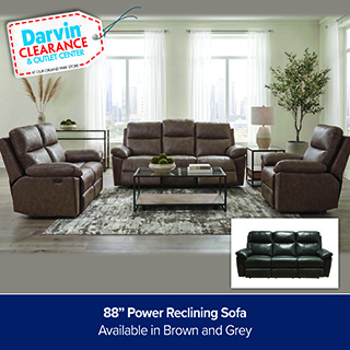 A promotional advertisement for the Darvin Clearance & Outlet Center featuring a power reclining living room furniture set. The image showcases a three-piece living room collection upholstered in a distressed brown faux-leather or fabric, including an 88-inch three-cushion reclining sofa in the center, a matching two-cushion reclining loveseat on the left, and a matching individual recliner armchair on the right. The furniture is arranged around a black metal coffee table with a glass top and a light wood lower shelf, resting on a mottled grey and beige abstract patterned area rug. The room is bright and modern with large windows dressed in sheer white curtains, white walls, a table lamp on an end table, and a tall plant in the background. A small rectangular inset image in the bottom right corner shows the same three-cushion sofa style available in a dark grey color. In the upper left corner, a white clearance price tag graphic with a red dashed border reads 'Darvin CLEARANCE & OUTLET CENTER'. A solid dark blue banner runs across the bottom with white text that reads,