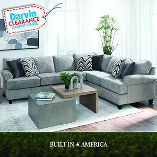 Darvin Clearance & Outlet Center logo, At our Grand Park Store, above a light gray sectional sofa with black and white chevron patterned throw pillows, wood and concrete coffee table, potted plant, in a room with large windows. Text reads BUILT IN AMERICA.