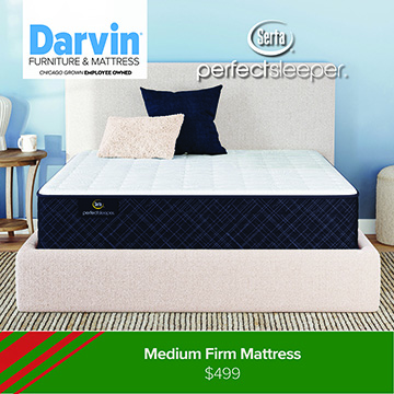 A Darvin Furniture & Mattress promotional image featuring a Serta Perfect Sleeper mattress displayed on a light beige upholstered bed frame. The mattress has a white top and dark blue patterned sides. Decorative pillows in navy and light beige are arranged at the head of the bed. The background shows a light blue wall and minimal bedroom decor. A green banner at the bottom reads: Medium Firm Mattress — $499.