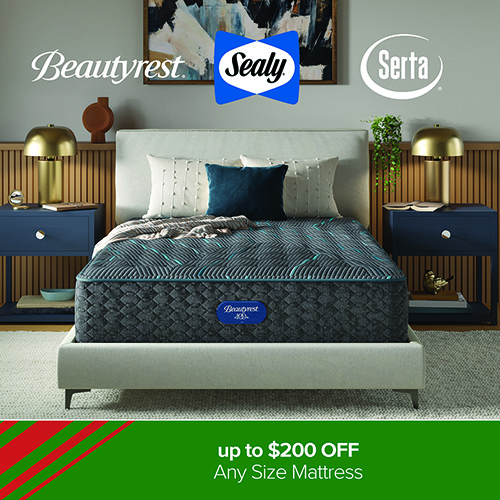 A bedroom display featuring a Beautyrest mattress shown on a light upholstered platform bed. The mattress has a dark blue quilted design. The bed is styled with neutral pillows and a dark blue accent pillow. On each side are navy blue nightstands with gold lamps and decorative items. Artwork hangs above the bed on a wood-paneled accent wall. Brand logos for Beautyrest, Sealy, and Serta appear at the top. A green banner along the bottom reads: up to $200 OFF Any Size Mattress.
