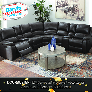 Promotional image of a black leather sectional sofa arranged in a living room with a round glass coffee table on a patterned area rug. A Darvin Clearance Outlet Center badge appears in the top left. Text along the bottom reads, Doorbuster – 100% Genuine Leather wherever the body touches. 2 Recliners, 2 Consoles & USB Ports.