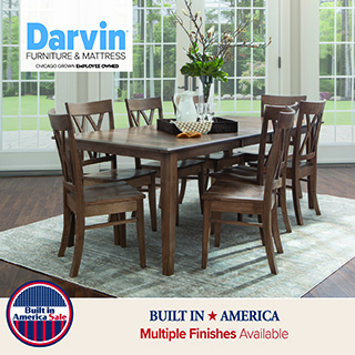 Rectangular solid wood dining table with six matching chairs in a bright dining room, displayed as a complete dining set