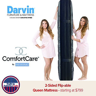 Two people holding a tall, foldable mattress upright, showing its thickness and construction with ComfortCare by Restonic branding