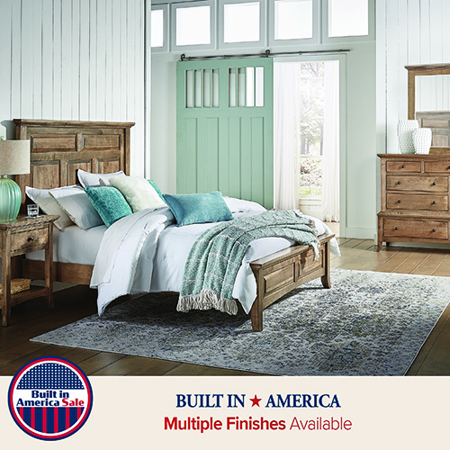 Solid wood panel bed with matching nightstands and dresser in a farmhouse-style bedroom, featuring a natural finish and clean, traditional lines
