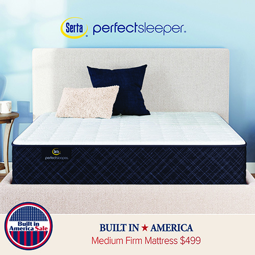 Close-up of a mattress with a light upholstered headboard and pillows, showing quilted top surface and Perfect Sleeper branding