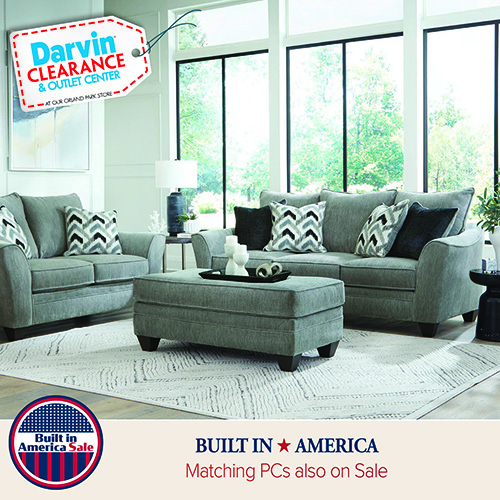 Long upholstered sofa with matching ottoman in a modern living room, styled with patterned accent pillows and neutral décor