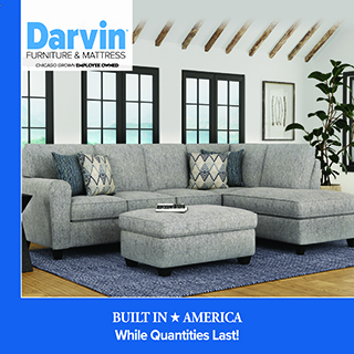 Promotional image for Darvin Furniture & Mattress showing a light gray sectional sofa with patterned accent pillows and a matching ottoman in a bright living room with large black-framed windows and a potted plant. The Darvin logo appears in the top left, and a blue banner at the bottom reads “Built in America — Built to Last!”