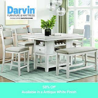 A promotional advertisement for Darvin Furniture & Mattress featuring a dining room set. The image showcases a counter-height wooden dining table in an antique white finish, which includes built-in storage with a drawer and a wine rack beneath the tabletop. Surrounding the table are four matching counter-height chairs with upholstered grey seats and backs, along with a matching upholstered dining bench in the foreground. The set rests on a teal patterned area rug in a bright dining room setting with large windows. The top left corner features the blue and black Darvin Furniture & Mattress logo with the text 'Chicago Grown Employee Owned'. A solid teal banner along the bottom reads '58% Off' followed by 'Available in an Antique White Finish' in white text.