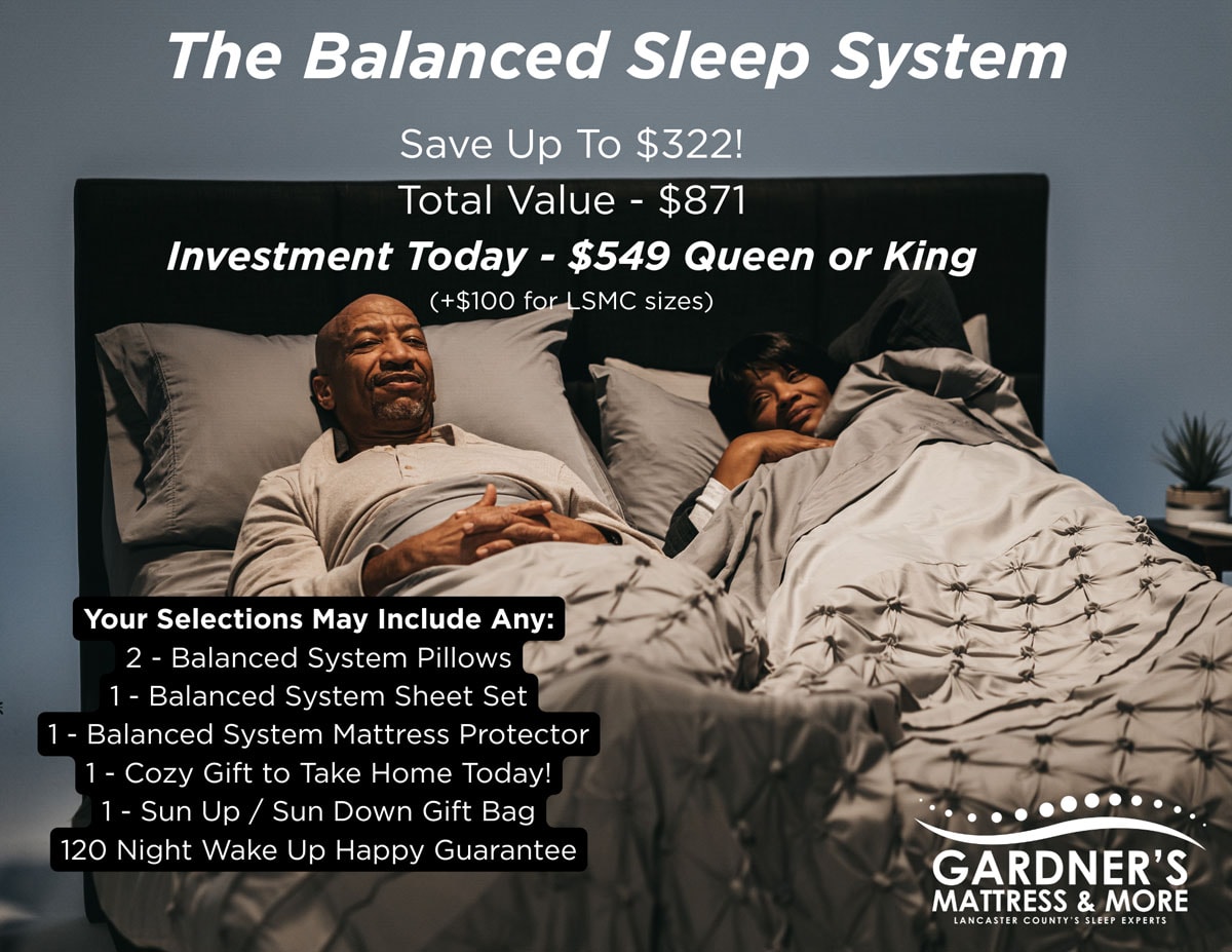 Gardner’s Mattress & More promotional graphic for The Balanced Sleep System. Two people relax in a bed with gray pillows and a quilted comforter. Text reads: The Balanced Sleep System. Save Up To $322. Total Value $871. Investment Today $549 Queen or King, plus $100 for LSMC sizes. Your selections may include: 2 Balanced System Pillows, 1 Balanced System Sheet Set, 1 Balanced System Mattress Protector, 1 Cozy Gift to Take Home Today, 1 Sun Up/Sun Down Gift Bag, and a 120 Night Wake Up Happy Guarantee. Gardner’s Mattress & More logo appears in the lower right corner.