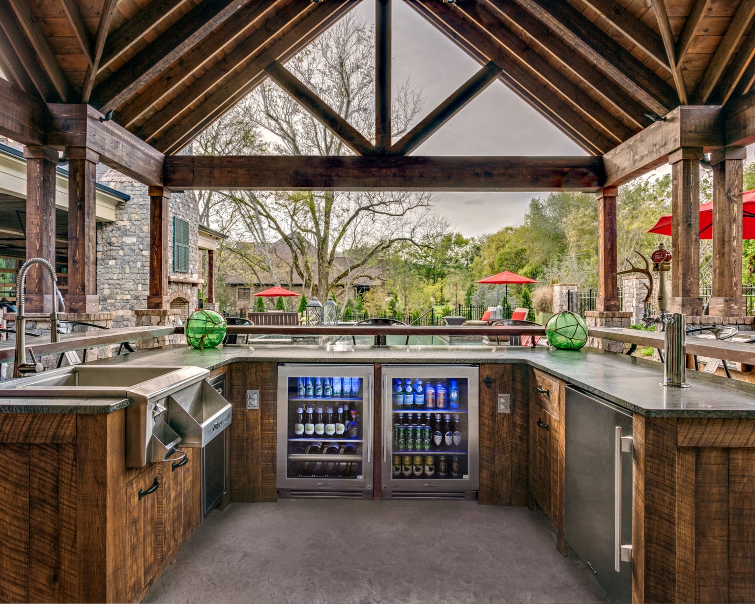 Luxury outdoor kitchen with grill and seating at dusk.