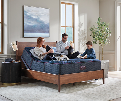 Black Friday Sale - Beautyrest lifestyle of mother, father, and son folding clothes happily on a mattress