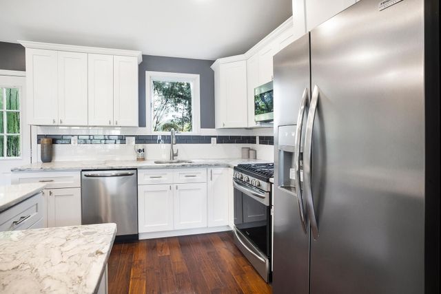View of a modern kitchen with white cabinetry and stainless steel appliances from Gerhard's Apliances