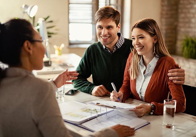 View of a couple discussing kitchen plans with a design expert.