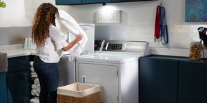 Woman opening Speed Queen washer door in a modern styled laundry room.